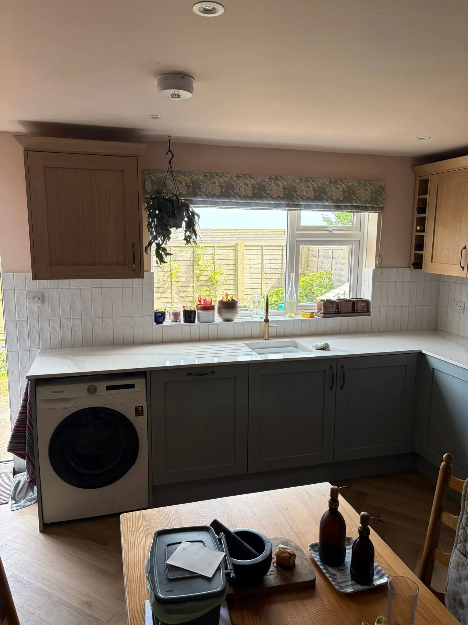 The sink run under the window, with a white worktop and space for the washing machine