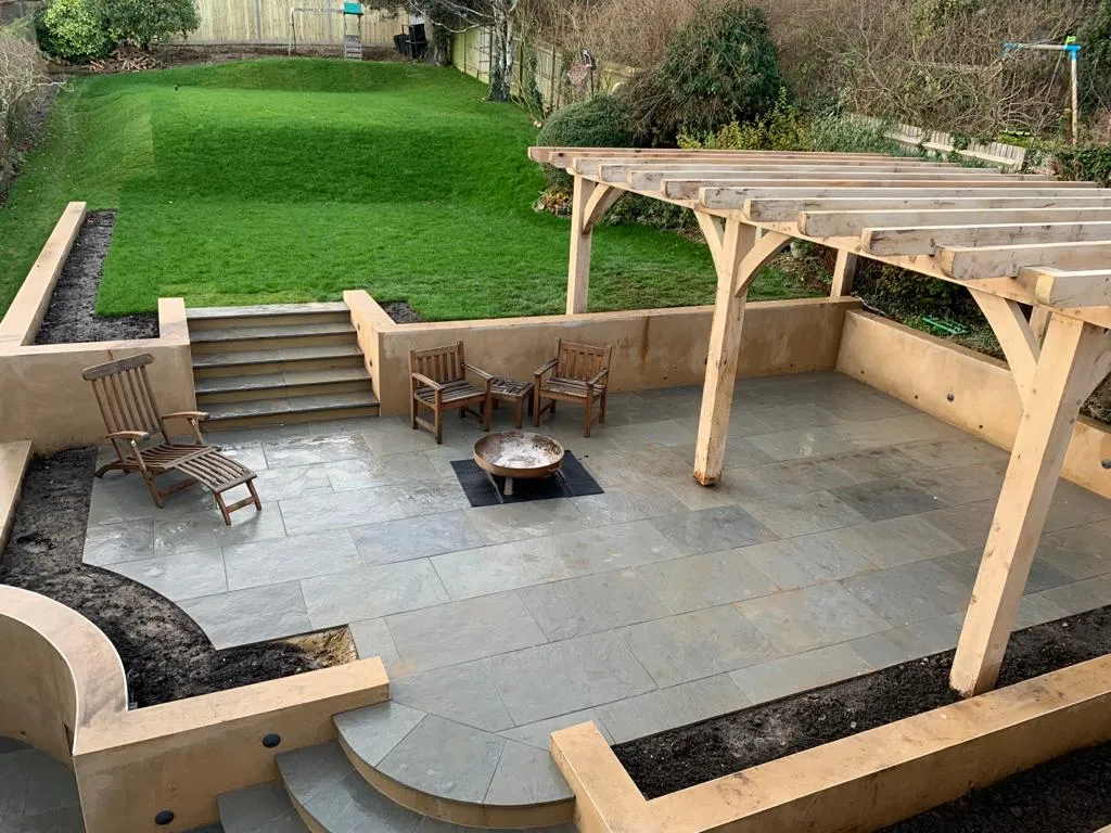 A landscaped garden with lawns, a patio and a pergola